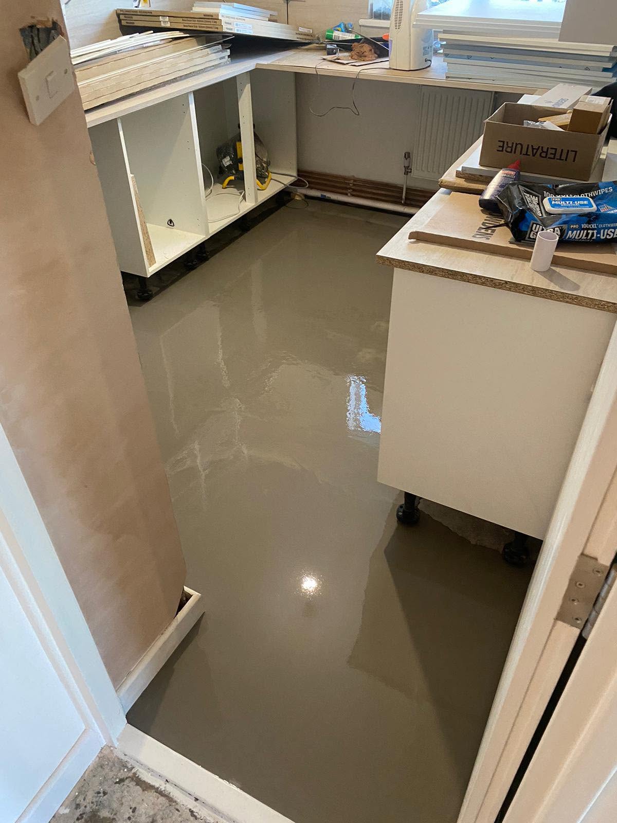 Freshly poured self-levelling screed in a kitchen being refitted