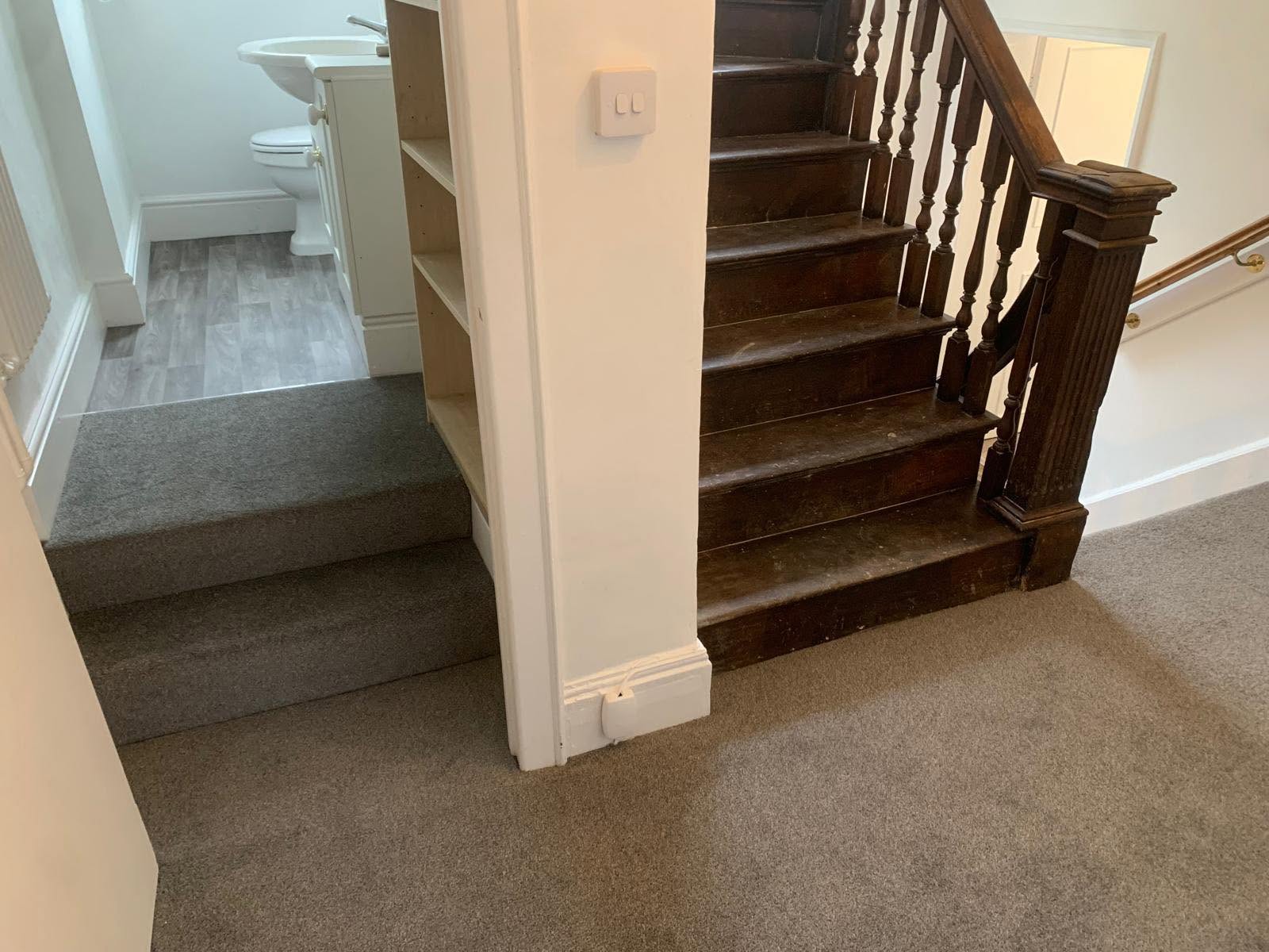 Carpeted half-landing and steps beside a dark wooden staircase