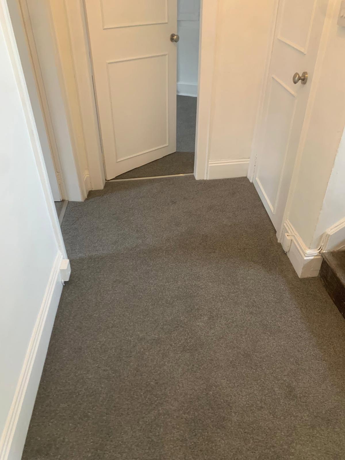 Grey carpet fitted along a hallway with panel doors